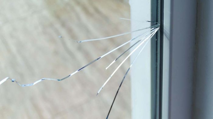 A detailed view of a cracked window pane in a residential setting