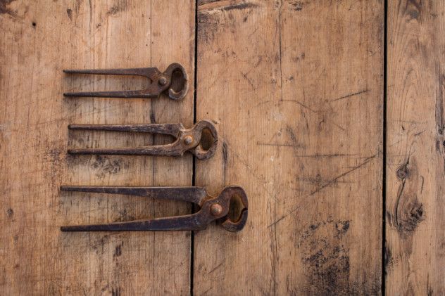 Three vintage pliers on a grunge wooden table