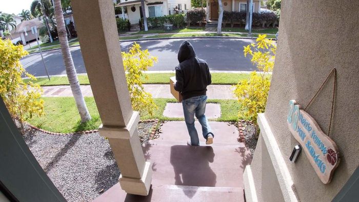 A hooded individual exits a porch