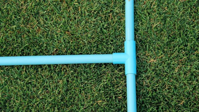 A PVC pipe with a T connector placed on the grass