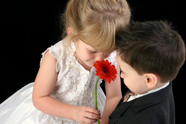 Adorable Young Children Smelling Daisy Together
