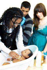 Childcare professionals guide young parents in mastering essential parenting techniques.