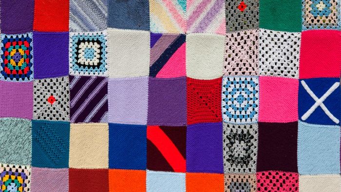 A vibrant, multicolored knitted quilt design.