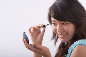 A woman in the process of applying mascara.