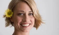 A woman with short hair wearing a flower tucked behind her ear