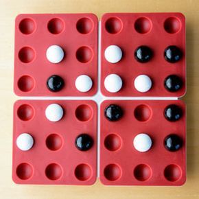 The Pentago board mid-game, featuring eight black and eight white marbles in play.