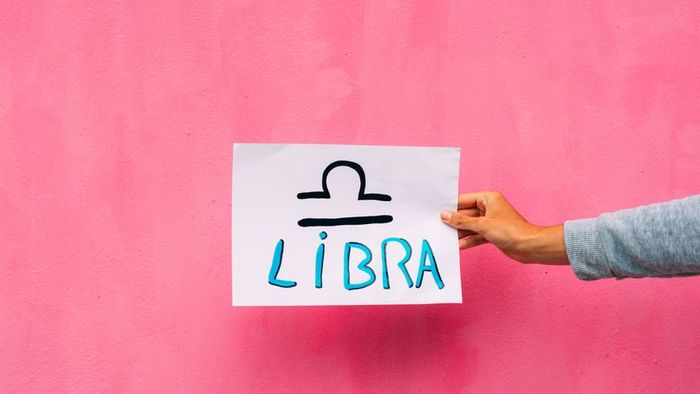 A depiction of the Libra symbol on white paper with a pink backdrop.