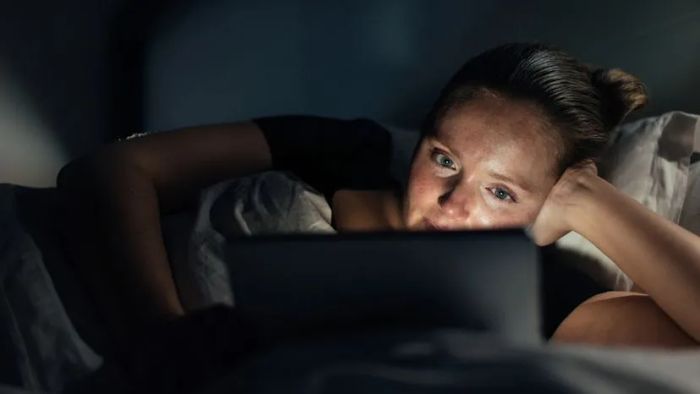 A woman enjoying a late-night movie on her laptop.