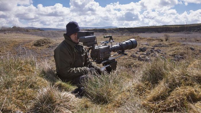 A man capturing footage in the middle of a dense forest.