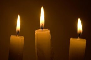 Three candles lit in memory of the passing of notable personalities.
