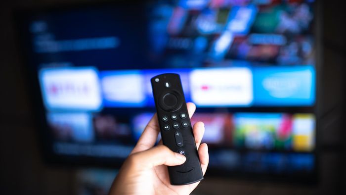 Amazon Fire Stick remote control with a television in the background