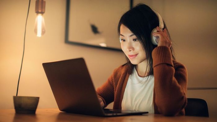 A woman enjoying a film on her laptop while wearing headphones.