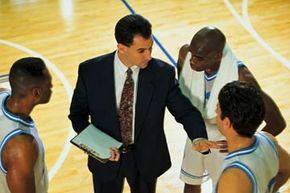 A coach addresses a group of basketball players during a training session.