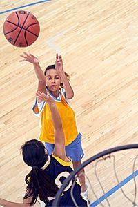 Two young girls engage in a game of basketball.