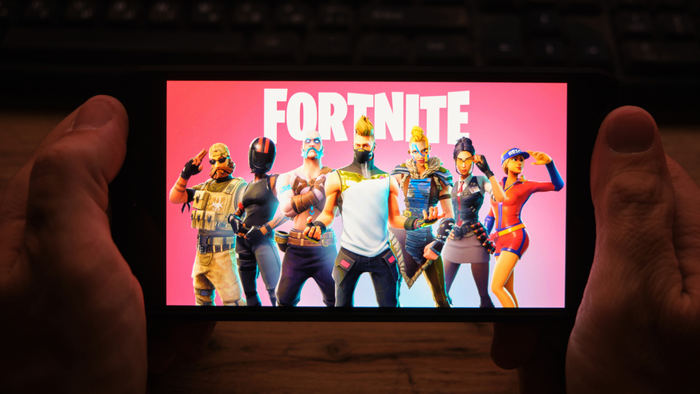 individual holding a smartphone displaying Fortnite gameplay