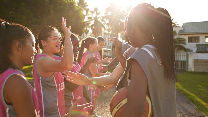 A team of women celebrating with high-fives after a thrilling basketball match