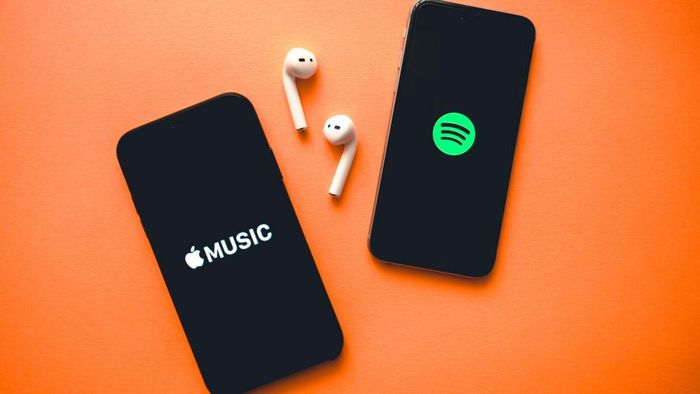 Two smartphones displaying screenshots of Apple Music and Spotify logos