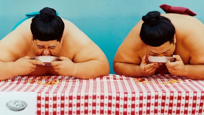 Two sumo wrestlers competing in a food-eating contest.