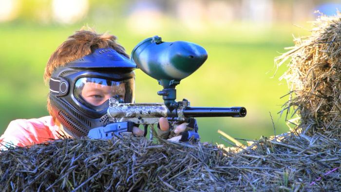 A child engaging in play with a paintball gun.