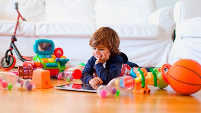 A child surrounded by an assortment of toys.