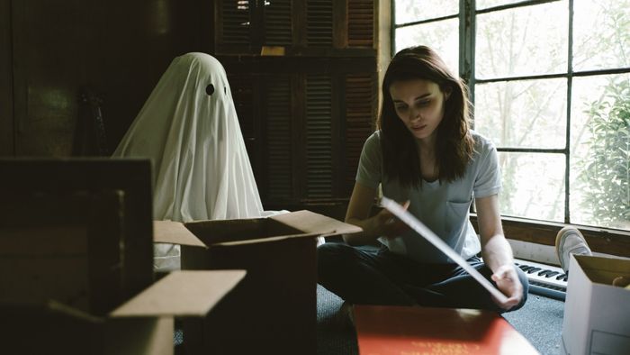 A spectral figure observes a person in a scene from A Ghost Story