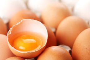 brown eggs with one cracked open to reveal the yolk and egg white