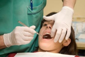 A woman undergoing a dental cleaning procedure at the dentist's office.