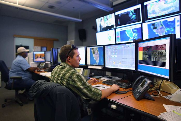 State officials in South Florida conduct a hurricane readiness exercise in a high-tech office equipped with numerous computer monitors.