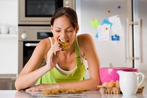 A woman enjoying cookies in her kitchen