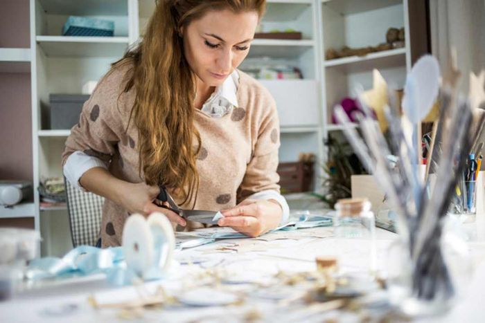 A woman cutting paper in her creative studio.