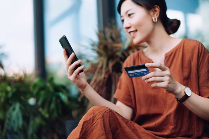 A woman using her smartphone to pay a bill with a credit card