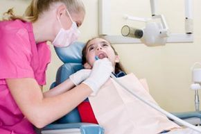 Dental hygienist performing a cleaning on a patient's teeth.