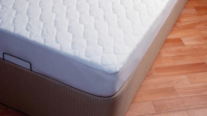 A mattress resting on a box spring placed on a wooden floor
