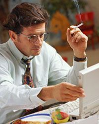 A man smoking while working on his computer