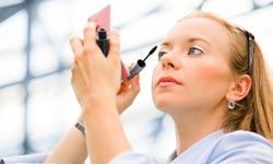 A businesswoman applying mascara