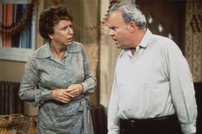 Characters from the TV series 'All in the Family' exchange glances.