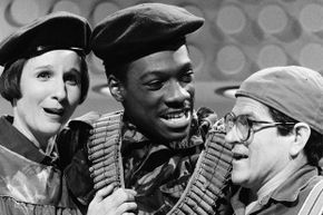 A black-and-white photo captures three comedians hugging in a scene from a 'Saturday Night Live' episode.