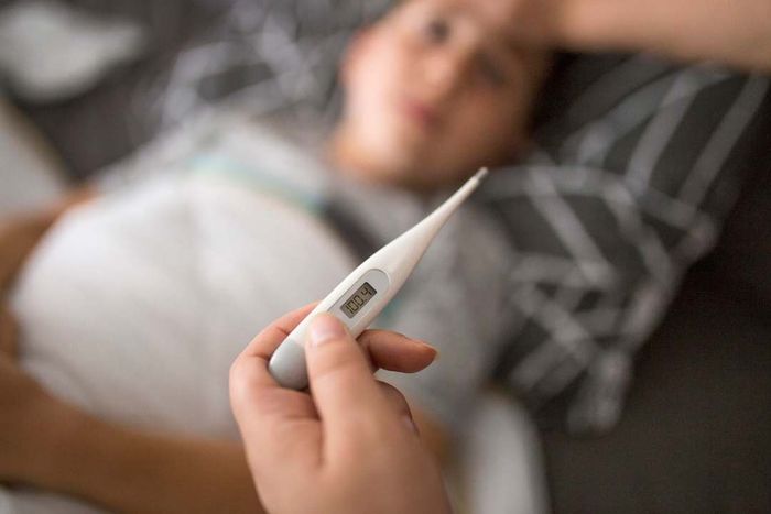 A woman checking her son’s temperature.