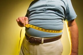 man measuring his large belly with a tape
