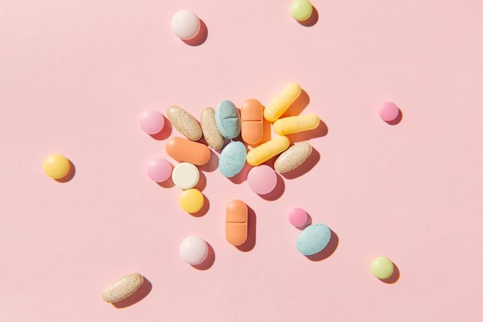 Vibrant pills and capsules displayed on a soft pink backdrop.