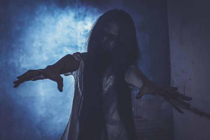 A chilling woman standing with her arms outstretched in the dark