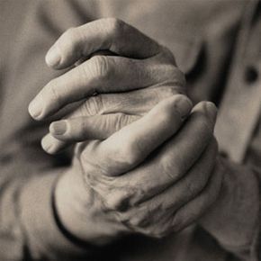 Close-up of a mature adult rubbing their hands in grainy black and white
