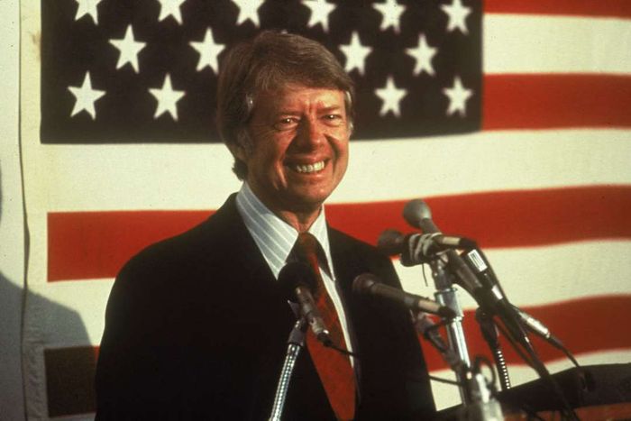 Jimmy Carter standing before an American flag.