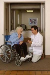 A woman in a wheelchair accompanied by a nursing home orderly