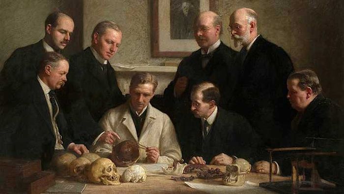 An image depicting the researchers who discovered and analyzed the Piltdown Man skull, with a portrait of Charles Darwin visible in the background.