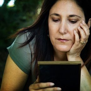 woman gazes sadly at a photograph