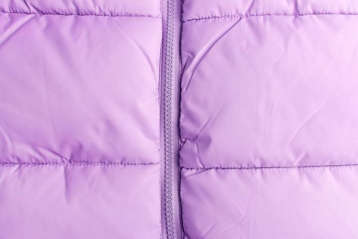 Close-up of a zipper on a quilted jacket, showcasing the texture of a puffer jacket.