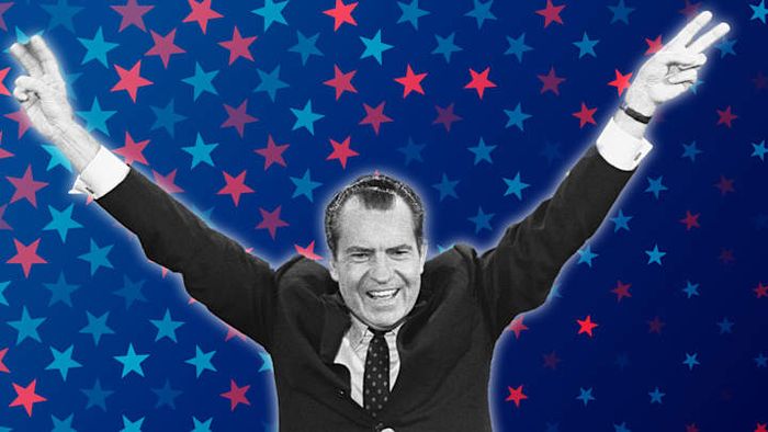 Richard Nixon displays his iconic “victory” hand gesture.