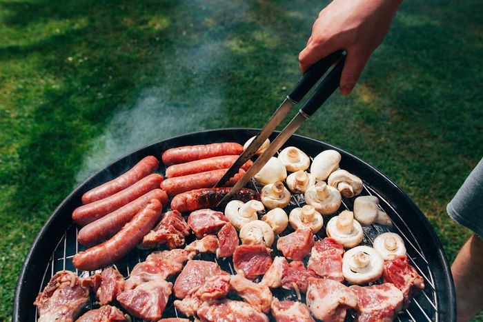 A BBQ with grilled meat, sausages, and mushrooms.