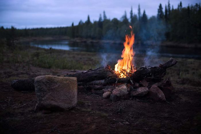 A campfire glowing on the edge of a river.